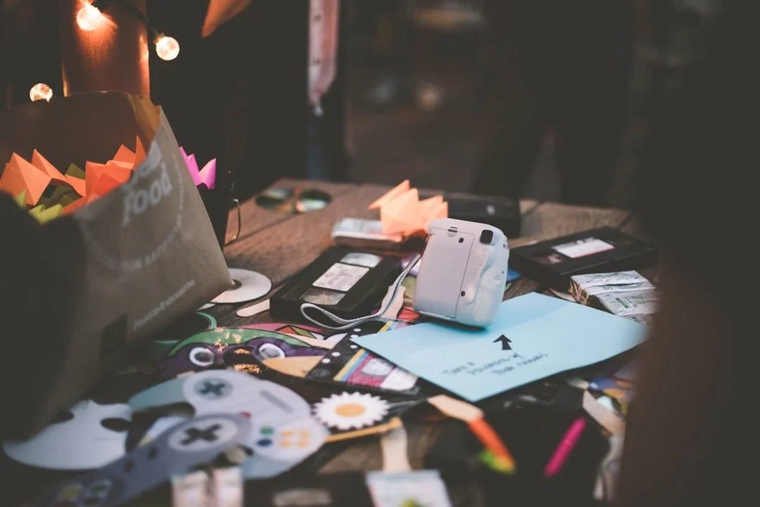 A table buried under photos, cables, pens and odds and ends