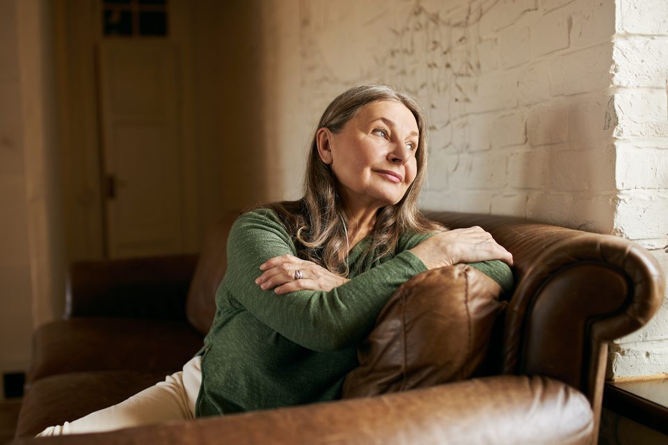 Older woman resting comfortably on a sofa in a calm, uncluttered room